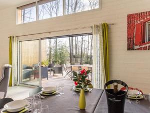 a dining room with a table with a vase of flowers at Grande maison en bois avec parc, terrasse, jeux et équipements modernes entre Nantes et Pornic - FR-1-306-1051 in Port-Saint-Père