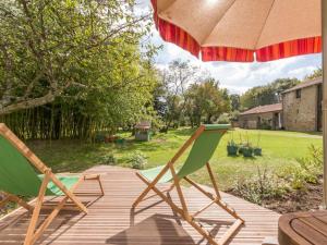 two lawn chairs sitting on a deck under an umbrella at Maison de Maître rénovée avec jardin, terrasse et équipements modernes, au calme de la campagne. - FR-1-306-928 in Saint-Père-en-Retz