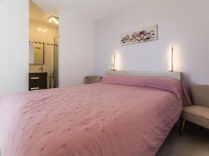 ein Schlafzimmer mit einem rosa Bett und einem Stuhl in der Unterkunft Appartements à Piriac-sur-Mer, plage, wifi, animaux acceptés - FR-1-306-1155 in Piriac-sur-Mer
