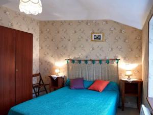 a bedroom with a blue bed with two colorful pillows at Charmante Maison Familiale à la Campagne, Proche Forêt, avec Wifi, Ping-Pong et Panier de Basket - FR-1-306-1152 in Le Gâvre