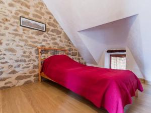 a bedroom with a red bed with a stone wall at Charmante chaumière rénovée près des marais salants avec jardin clos et équipements modernes - FR-1-306-1072 in Guérande