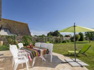 a table with white chairs and a green umbrella at Chaumière Typique en Brière avec Cheminée, WiFi, et Terrasse - Idéal Familles - FR-1-306-1131 in Saint-Joachim