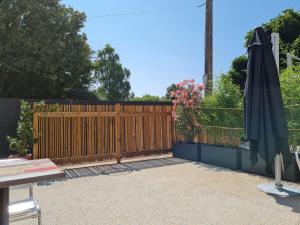 ein Holzzaun mit einem Regenschirm in einem Hof in der Unterkunft Studio cosy avec mezzanine, cour privative et espace vert à Rochetrejoux - FR-1-426-478 in Rochetrejoux