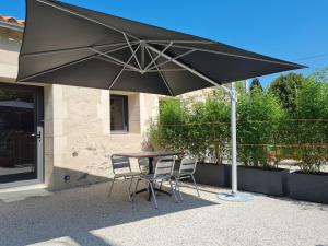 einen Tisch und zwei Stühle unter einem Schirm in der Unterkunft Charmant studio rénové avec mezzanine, cour privative et parking à Rochetrejoux - FR-1-426-479 in Rochetrejoux