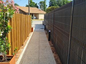 Ein Zaun mit einem Ziegelsteinweg neben einem Zaun, einem gmaxwell, einem gmaxwell-gmaxwell. in der Unterkunft Charmant studio rénové avec mezzanine, cour privative et parking à Rochetrejoux - FR-1-426-479 in Rochetrejoux + 7 Fotos