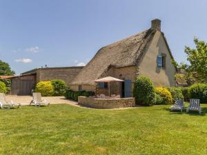 a house with a thatched roof with chairs in the yard at Chaumière typique avec jardin clos, proche Guérande et La Baule, idéale pour familles et cyclistes - FR-1-306-1091 in Saint-Lyphard