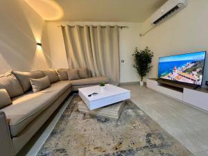 un salon avec un canapé et une télévision à écran plat dans l'établissement Madinaty Luxury Escape 2BR, à Madinaty