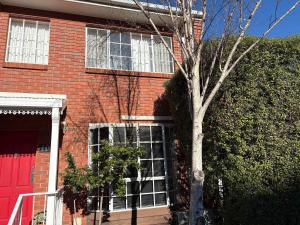 a red brick building with a tree in front of it at Cosy renovated 2 bed villa in superb location in Hobart