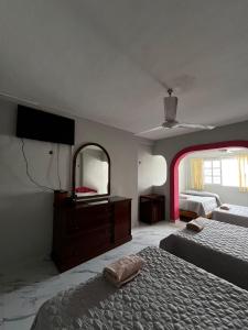 a bedroom with two beds and a mirror at Hotel Cancún Rosa in Cancún