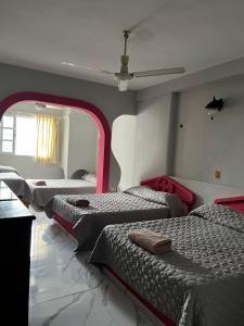 a room with four beds in a room with a ceiling at Hotel Cancún Rosa in Cancún