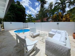 un patio con un divano, sedie e un tavolo di Villa Allegria Los Lagos 57 a La Romana