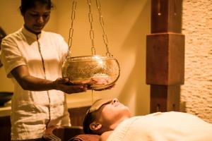 a man laying on a bed in a room with a pot at Anantara Peace Haven Tangalle Resort in Tangalle