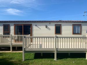 a white house with a porch and a fence at Gbk caravans in Rhyl
