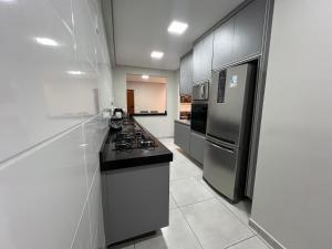 a kitchen with a stove and a refrigerator at Apartamento próximo avenida da Semi Jóia in Limeira