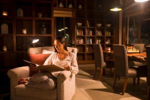 a woman sitting in a chair reading a book at Anantara Peace Haven Tangalle Resort in Tangalle