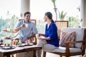 a man and a woman sitting around a table with food at Anantara Peace Haven Tangalle Resort in Tangalle