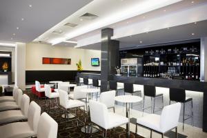 um restaurante com cadeiras brancas e um bar em Mantra Melbourne Airport em Melbourne