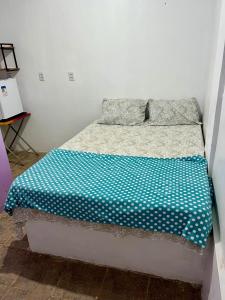 a bed with a blue and white sheets and pillows at Pousada Rosa de Saron - Algodoal in Algodoal