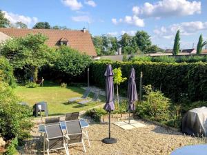 un groupe de parasols et de chaises dans un jardin dans l'établissement Maison rénovée à Moulins avec jardin et véranda - FR-1-489-469, à Moulins