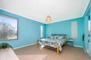 a blue room with a bed and a window at Break-A-Way - Coastal comfort in lancelin in Lancelin