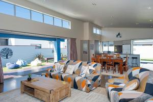 Una sala de estar con dos sofás y una mesa. en Ocean Blue, sunny beach home close to surf & shops, en Waihi Beach