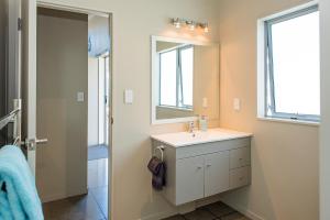 un baño con lavabo y espejo en Ocean Blue, sunny beach home close to surf & shops, en Waihi Beach 24 fotos más