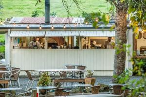 un grupo de mesas y sillas frente a un restaurante en Ocean Blue, sunny beach home close to surf & shops, en Waihi Beach