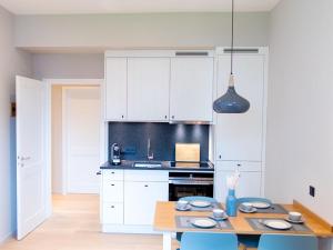 eine Küche mit weißen Schränken und einem Holztisch in der Unterkunft Lüttjer Kaiser Comfortable holiday residence in Norderney