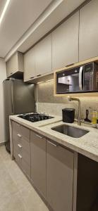 a kitchen with a sink and a microwave at Um lugar de charme e aconchego - Gérbera! in Brasilia