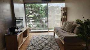 a living room with a couch and a large window at Espectacular Departamento en Concord Pilar con cochera in La Lonja