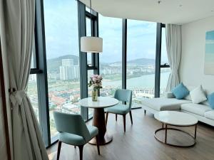 a living room with a couch and a table and chairs at Spring ALacarte Ha Long Luxury Studio in Ha Long