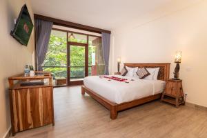 a bedroom with a bed with red flowers on it at Umah Temuku Ubud in Ubud