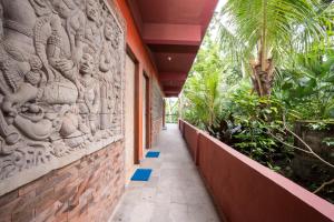 a walkway in a building with a wall with reliefs at Umah Temuku Ubud in Ubud