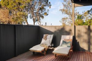 two chairs on a deck with a fence at Valentine Sandcastles - Your Group Beach Escape! in Rye