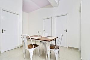 a white dining room with a wooden table and chairs at Hotel O Leva Homes Near Baiyappanahalli Metro Station in Bengaluru