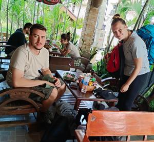 a man sitting at a table in a restaurant with a woman at TR Guesthouse in Sukhothai