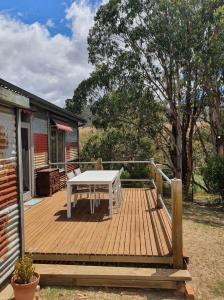a wooden deck with a white table on a house at Homeo Alpine Cottage in Omeo
