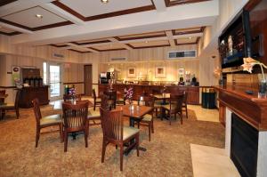 a dining room with tables and chairs and a bar at Country Inn & Suites by Radisson, Conway, AR in Conway