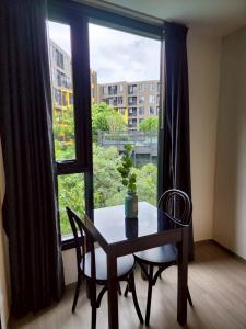 un tavolo e delle sedie in una stanza con una grande finestra di The Base Central Phuket-B42WL a Ban Rangeng