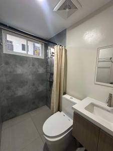 a bathroom with a toilet and a shower and a sink at 2 Bedroom Family Suite with Balcony in Lapu Lapu City