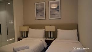 two beds in a hotel room with two lamps at Address Beach Resort Fujairah Apartment by Blue World - 1 in Fujairah