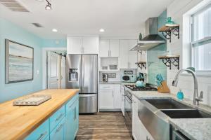 una cocina con armarios blancos y electrodomésticos azules en Come Sail Away, en Destin