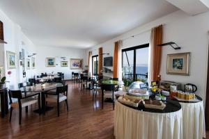 un comedor con mesas y sillas y el océano en Hotel Villa Carlotta, en Torri del Benaco
