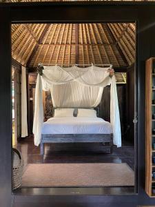 a bed in a room with a canopy at Heliconia, at T house kaja in Ubud