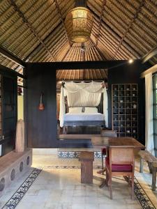 a bedroom with a bed and a wooden table at Heliconia, at T house kaja in Ubud
