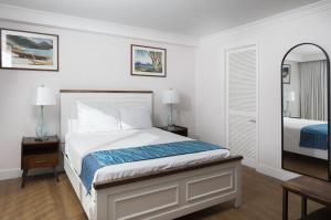 a white bedroom with a bed and a mirror at Refreshing Royal Garden Studio condo in Honolulu +25 photos