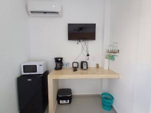a room with a desk with a microwave and a tv at Casa Linda Isla-Room Palmera-Shared Pool in Isla Mujeres
