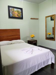 a bedroom with a white bed and a mirror at Hospedaje Bello Horizonte in Tarapoto