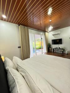 a bedroom with a large white bed and a television at Nira Meraki Aruna in Bedoyo