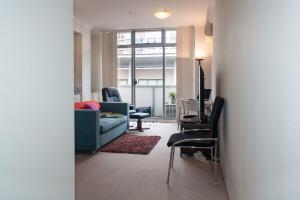 un salon avec un canapé bleu et des chaises dans l'établissement Oxford St Apartment with Gym Spa Pool, à Sydney